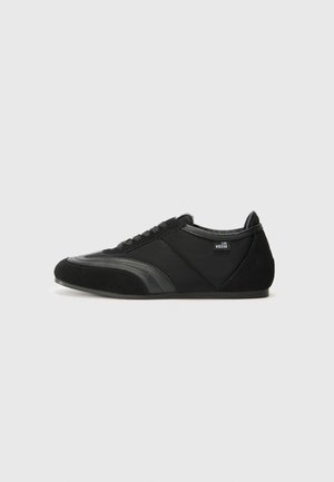 Sneaker neri realizzati in tessuto morbido e suede, con profilo basso, punta rotonda, design con lacci e dettagli testurizzati ai lati.