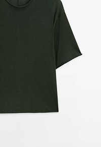 Mørkegrøn kortærmet t-shirt med rund hals og ensartet design, synlig fra brystet til midt på kanten mod en hvid baggrund.