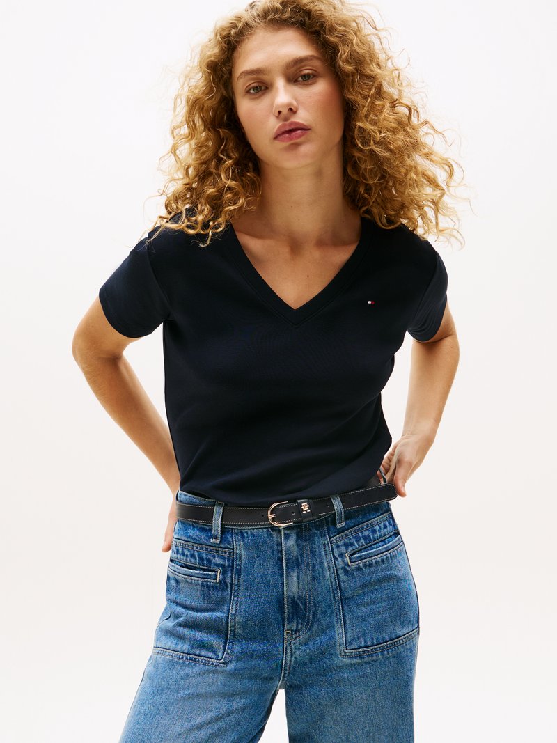 Μπλε T-shirt V με βαθύ λαιμό, φτιαγμένο από βαμβάκι, συνδυασμένο με ψηλόμεσα μπλε τζιν. Το σύνολο διαθέτει μία μαύρη ζώνη με ασημένια κυκλική πόρπη.