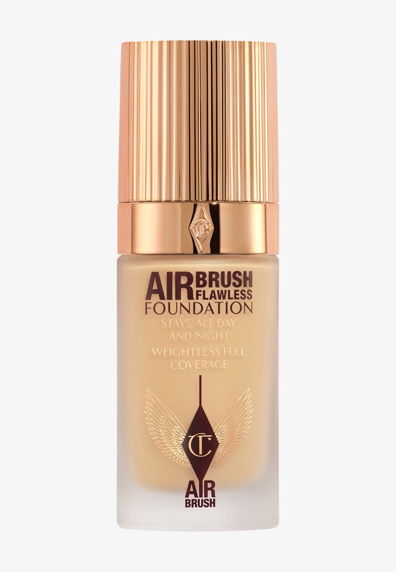 Airbrush Flawless Foundation in a glass bottle with a gold ribbed cap; cream shade with embossed branding and winged design accents.