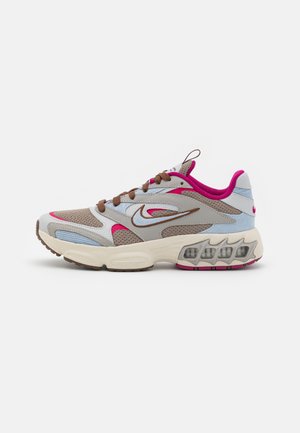Beige en lichtblauwe sneaker met roze accenten, bovenwerk van gaas, bruine veters, gevoerde zool en zichtbare luchtzakken voor extra ondersteuning.