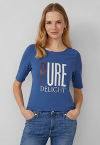 T-shirt en coton bleu à manches courtes avec le texte "PURE DELIGHT" dans différentes polices et couleurs. Coupe décontractée avec un col rond.