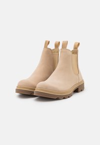 Beige Chelsea boty vyrobené z hladké kůže, s elastickými bočními panely a poutky. Pevná hnědá gumová podrážka má drážky pro lepší trakci.
