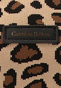 Tela de estampado de leopardo en beige, con manchas en marrón oscuro y beige. Incluye una etiqueta negra con texto en relieve dorado que dice "Carmina Jhilton."