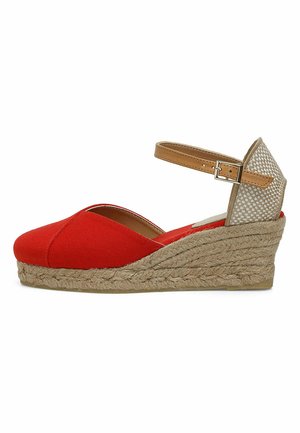 Rode canvas wedge-schoen met een gevlochten jute zool, verstelbare bruine enkelband en een gewoven mesh achterdetail. Zachte, gestructureerde afwerking.