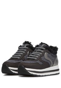 Zwarte en grijze sneakers met een gestructureerde afwerking, voorzien van zachte accenten, metalen details en een gevoerde kraag. Dikke witte tusenlaag, rubberen buitenzool.