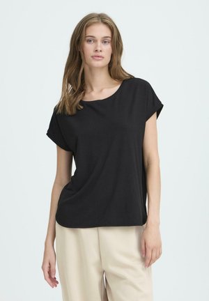 Schwarzes Kurzarm-T-Shirt aus weichem Stoff, mit rundem Ausschnitt und lockerer Passform, kombiniert mit hellbeigen Hosen.