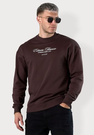 Sweatshirt marron avec un col rond côtelé et des manches longues, présentant une impression de texte blanc "Esteem Finesse Creative Craft & Art" sur le devant.