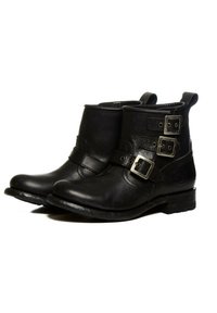 Botas de tobillo de cuero negro con dos hebillas plateadas, punta redondeada y un tacón bajo de bloque. Acabado texturizado con detalles de costura en contraste.