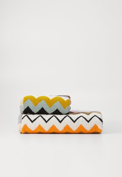 To settede håndklær med zigzag-mønster; det øverste håndkleet i grått, sennepsgul og svart; det nederste håndkleet i oransje, hvitt og svart. Teksturet stoff.