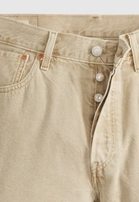 Jeanși din denim bej, cu închidere prin buton, nituri de cupru, o textură diagonală subtilă și un design cu picior drept.