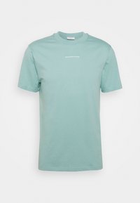 T-shirt in cotone verde chiaro con colletto rotondo e maniche corte; presenta la scritta bianca "SANDRO PARIS" sul petto. Tessuto liscio, senza decorazioni.