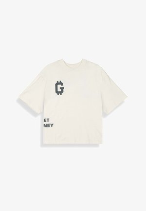 Oversizowa koszulka w kolorze kremowym z czarnym pikselowym literą "G" oraz częściowym czarnym napisem "ET NEY" na przodzie, krótkimi rękawami i okrągłym dekoltem.