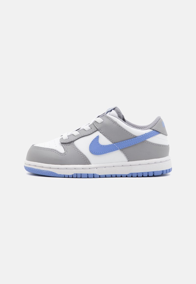 Sneaker grigie e bianche con il baffo Nike blu, tomaia in pelle, punta rotonda e superficie strutturata. Presenta una suola intermedia bianca e suola esterna blu.