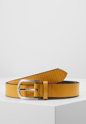 Tanfarvet læderbælte med en sølvfarvet rektangulær metalspænde, viklet sammen og hvilende på en hvid overflade mod en ensfarvet baggrund.