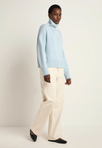 Light blue turtleneck sweater with ribbed cuffs and hem, paired with cream wide-leg trousers and black pointed-toe flats.