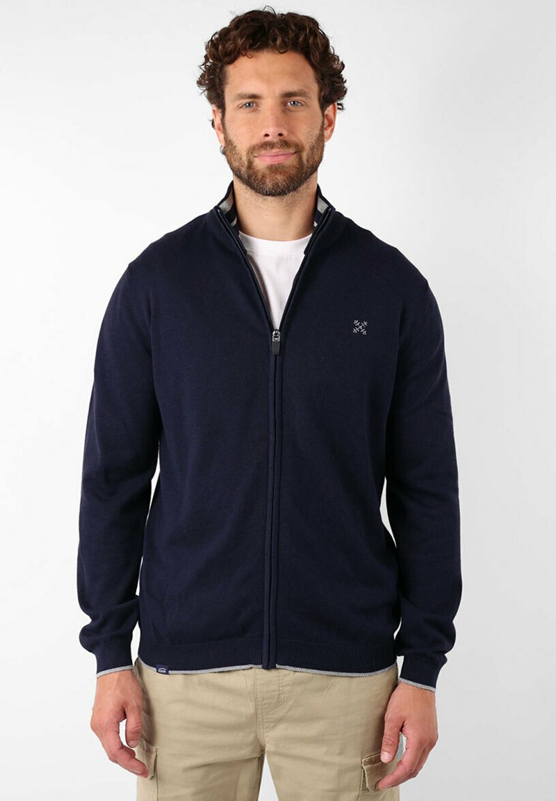 Pull zippé marine avec un col haut, des poignets côtelés et un petit logo sur la poitrine gauche. Matière douce et design ajusté.