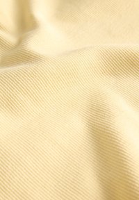 Tissu textile de couleur jaune pâle avec une surface texturée et côtelée, présentant une apparence douce, légère et une légère brillance.