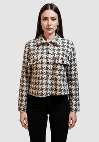 Chaqueta corta marrón y blanca con un diseño de pata de gallo, que cuenta con cuello, dos bolsillos en el pecho con botón y mangas largas.