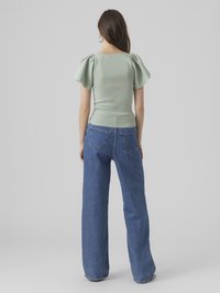 Myntegrønn, tettsittende topp med pufferm; paired med høyt liv, vide ben blå denim jeans. Enkelt, rent design uten dekorasjoner.