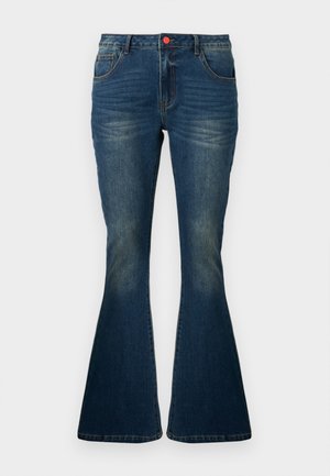 Jean en denim bleu foncé avec légère décoloration, jambes évasées, poches avant et fermeture par un bouton rouge à la taille.