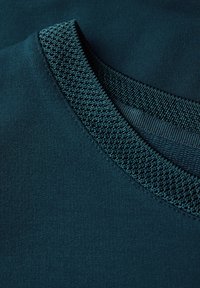 Tessuto verde scuro con un colletto lavorato a maglia testurizzato. Il corpo principale liscio contrasta con il design strutturato del collo, evidenziando i dettagli.