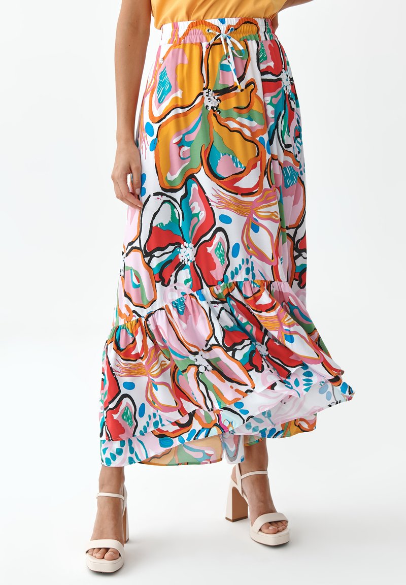 Jupe maxi florale colorée avec un design à volants, une taille élastique avec cordon de serrage et un ourlet fluide. Les motifs incluent des teintes vibrantes de rose, vert et bleu.