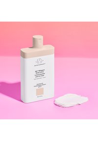 Eine weiße Flasche mit Körperlotion und einem beigefarbenen Deckel, beschriftet mit "Sili™ Whipped Body Lotion", auf einem rosafarbenen Hintergrund ruhend, mit einem Klecks Lotion in der Nähe.