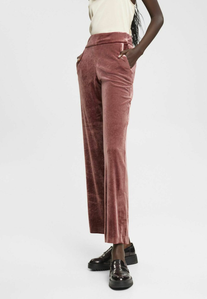 Samtige, hoch taillierte Hose in staubigem Rosé, mit seitlichen Taschen und geradem Bein. Kombiniert mit schwarzen Loafers.