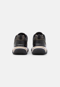 Scarpe da ginnastica nere con un design elegante, dettagli in pelle verniciata, tallone testurizzato e rifiniture dorate e bianche sulla suola.