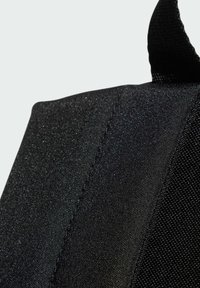 Tessuto nero con una superficie testurizzata presenta un aspetto leggermente lucido. Il materiale è resistente, con cuciture visibili e un bordo rinforzato.