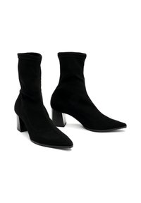 Bottes noires à la cheville avec une tige ajustée, un design à bout pointu, un tissu texturé et un talon haut épais. Détails des coutures visibles sur les côtés.