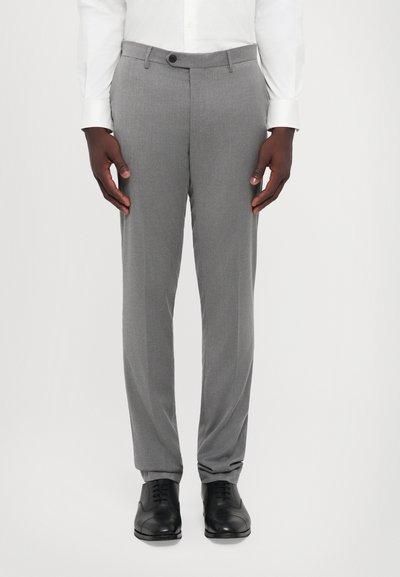 Grå dressbukser lavet af tekstureret stof, med en slim fit og en enkelt knaplukning. Parret med sorte lædersko.