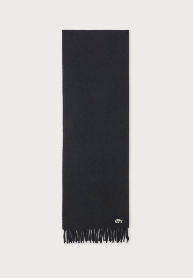 Écharpe rectangulaire noire avec extrémités à franges et petit logo crocodile vert près d'un bord sur fond neutre.