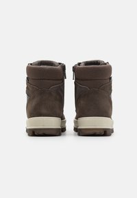 Botas de ante marrones con un collar acolchado, cierre de cremallera y una suela de goma texturizada. Acentos de malla distintivos en la parte superior.