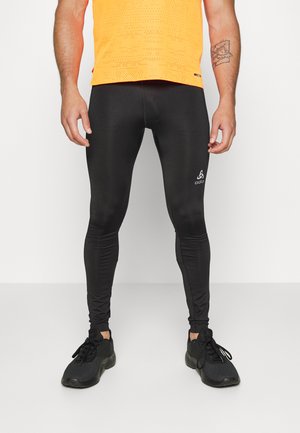 Schwarze Sportleggings aus einem glatten, dehnbaren Material. Mit einem Logo am Unterschenkel und einer figurbetonten Silhouette.