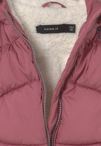 Rosa puffer vest med en blød hvid fleeceforing. Udstyret med en lynlås foran med klare perler og en etiket med teksten "name it."