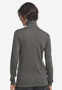 Grå polotröja i ett slätt stickat tyg, med långa ärmar och en kroppsnära design. Ribbad mudd och nederkant ger textur.