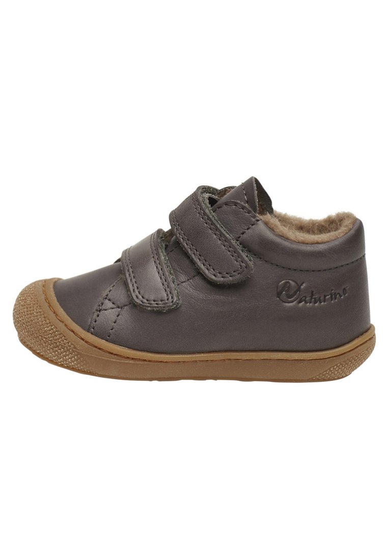 Scarpa per bambini in pelle grigia con due cinturini in velcro, interno morbido e suola in gomma con finitura testurizzata. Presenta un design della punta arrotondata.