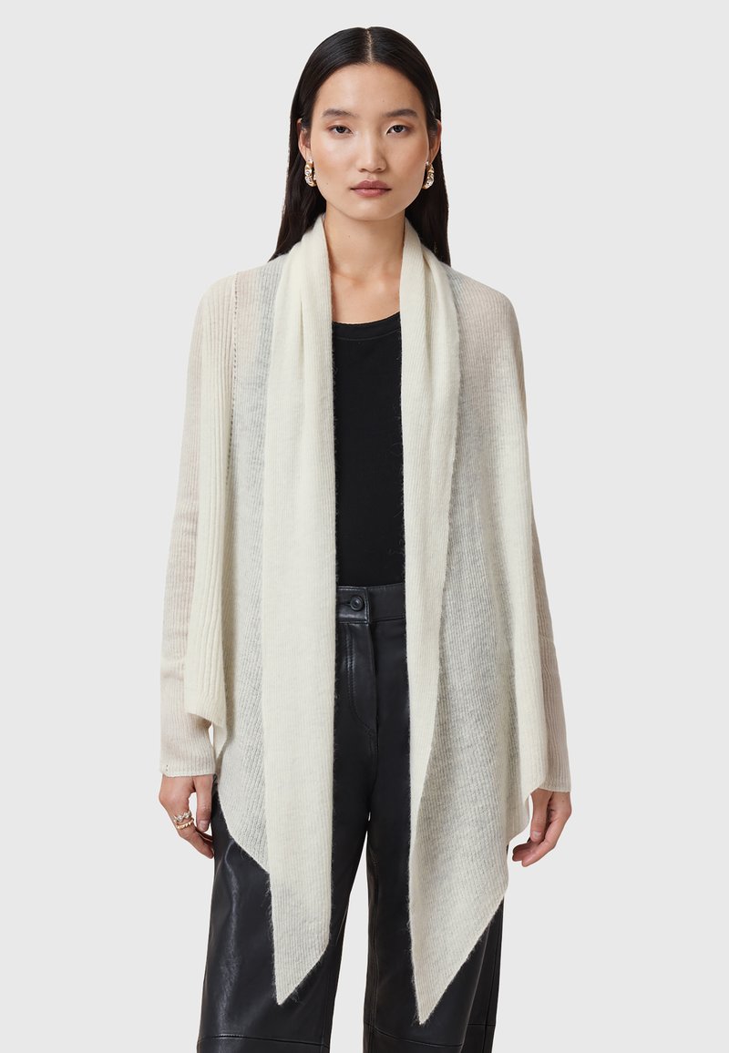 Ljust beige stickad cardigan med öppen front, lång ärm och draperad nederkant. Texturerat material med subtila ränder och mjuk yta.