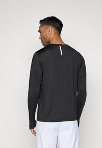 Black, long-sleeve shirt made of lightweight fabric, featuring a crew neck and a vertical white zipper detail at the back neck.