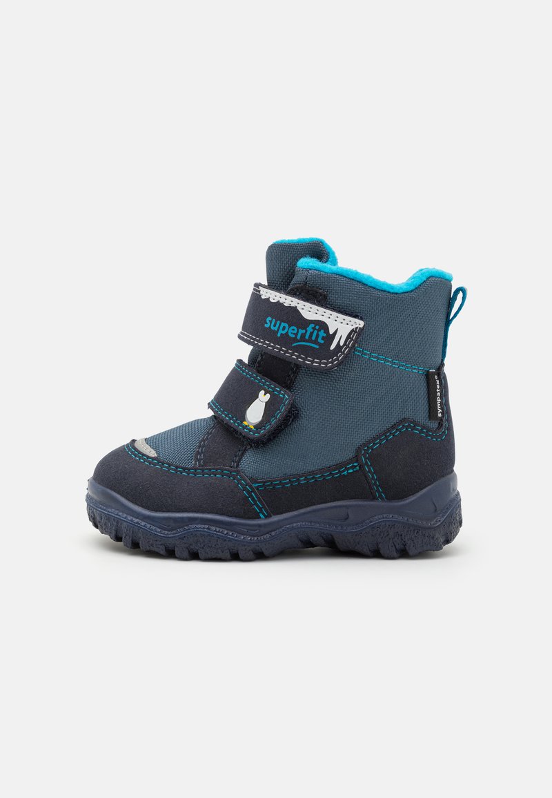 Botas infantiles en navy y azul con dos tiras de Velcro, puntera reforzada, suela de goma texturizada y forro de forro polar alrededor del tobillo.