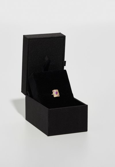 Goldring mit quadratischem Design, das ein lila Herz zeigt, präsentiert in einer mit schwarzem Samt ausgekleideten Schmuckschatulle. Die Box hat eine strukturierte, matte Oberfläche.