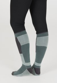 Socks korkeudeltaan polviin saakka on varustettu geometrisella kuviolla teal, harmaan ja tummanharmaan sävyissä. Teksturoitu kangas sisältää ribbaustakin ja pehmeän pinnan.