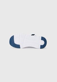 Suela de zapatilla blanca con almohadillas de goma azul marino en el talón y la punta, con patrones de agarre texturizados y el nombre de la marca grabado.