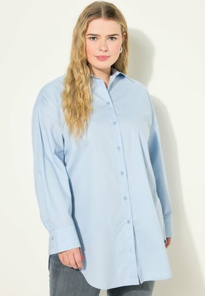 Camicia azzurro chiaro con maniche lunghe, colletto a punta e taglio dritto. Realizzata in un tessuto leggero con una texture liscia.