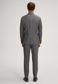 Completo grigio a righe con vestibilità su misura, caratterizzato da una giacca monopetto e pantaloni abbinati. Tessuto liscio e design elegante.