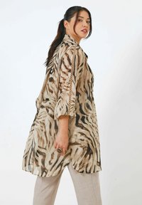 Durchsichtige, beige Kimono-bluse mit einem auffälligen Zebramuster, breiten Ärmeln und abgerundetem Saum, verziert mit Spitzenakzenten an den Seiten.