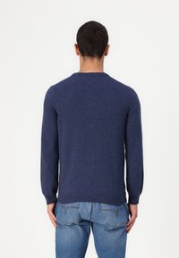 Marinblått stickat tröja med långa ärmar och rund halsringning, med ribbad nederkant och ärmslut, visad bakifrån.