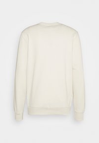 Sweat-shirt long manches longues couleur blanc cassé uni, avec poignets et ourlet côtelés, vu de dos sur un fond clair neutre.